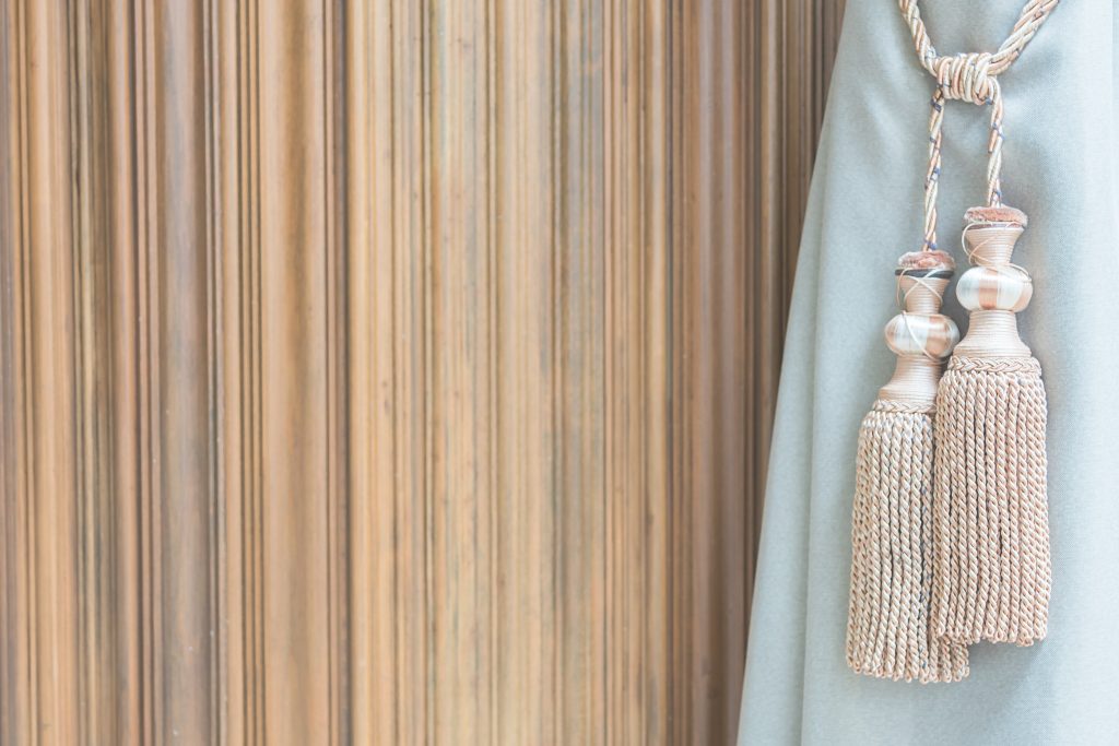 Une paire d'embrasses de rideaux élégantes en tissu beige, attachées à un rideau blanc fluide, ajoutant une touche de sophistication à la décoration de fenêtre