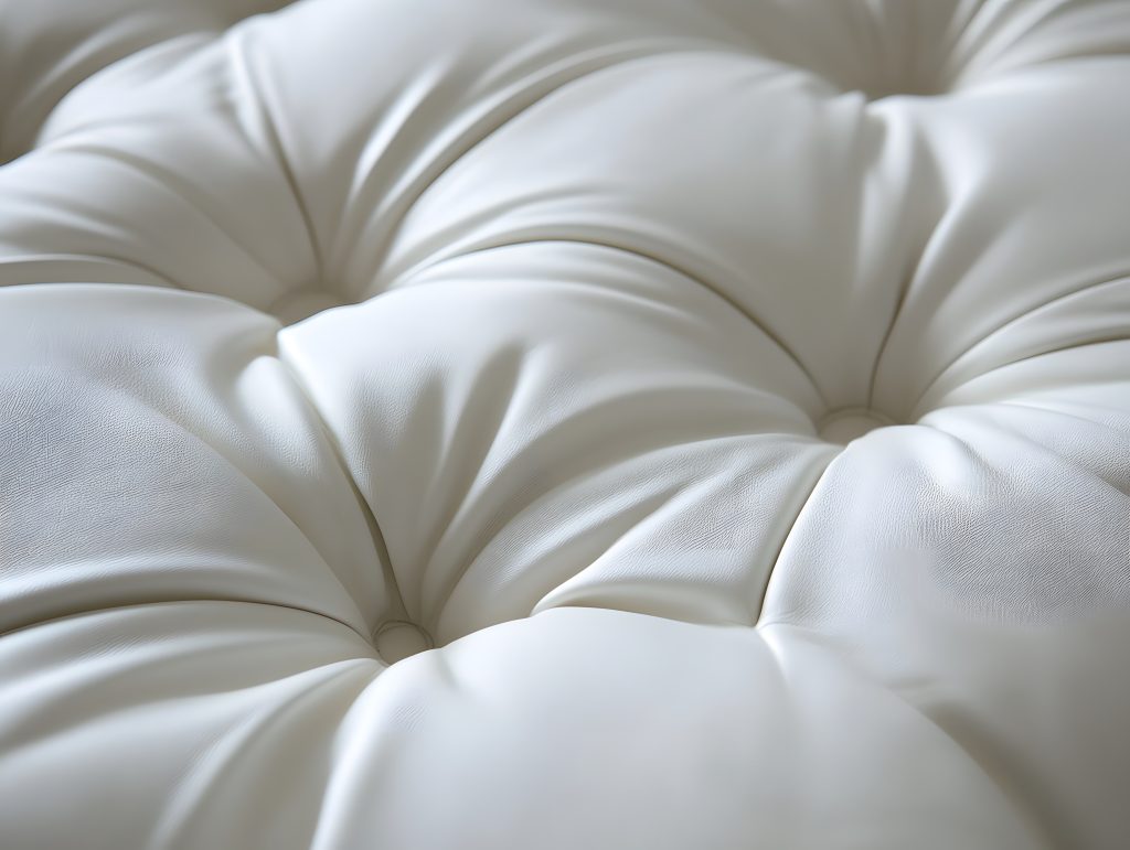 Gros plan sur un capitonnage blanc luxueux, mettant en valeur les plis soignés et la texture raffinée d'un rembourrage, parfait pour un tapissier décorateur souhaitant exhiber son savoir-faire en upholstery haut de gamme.